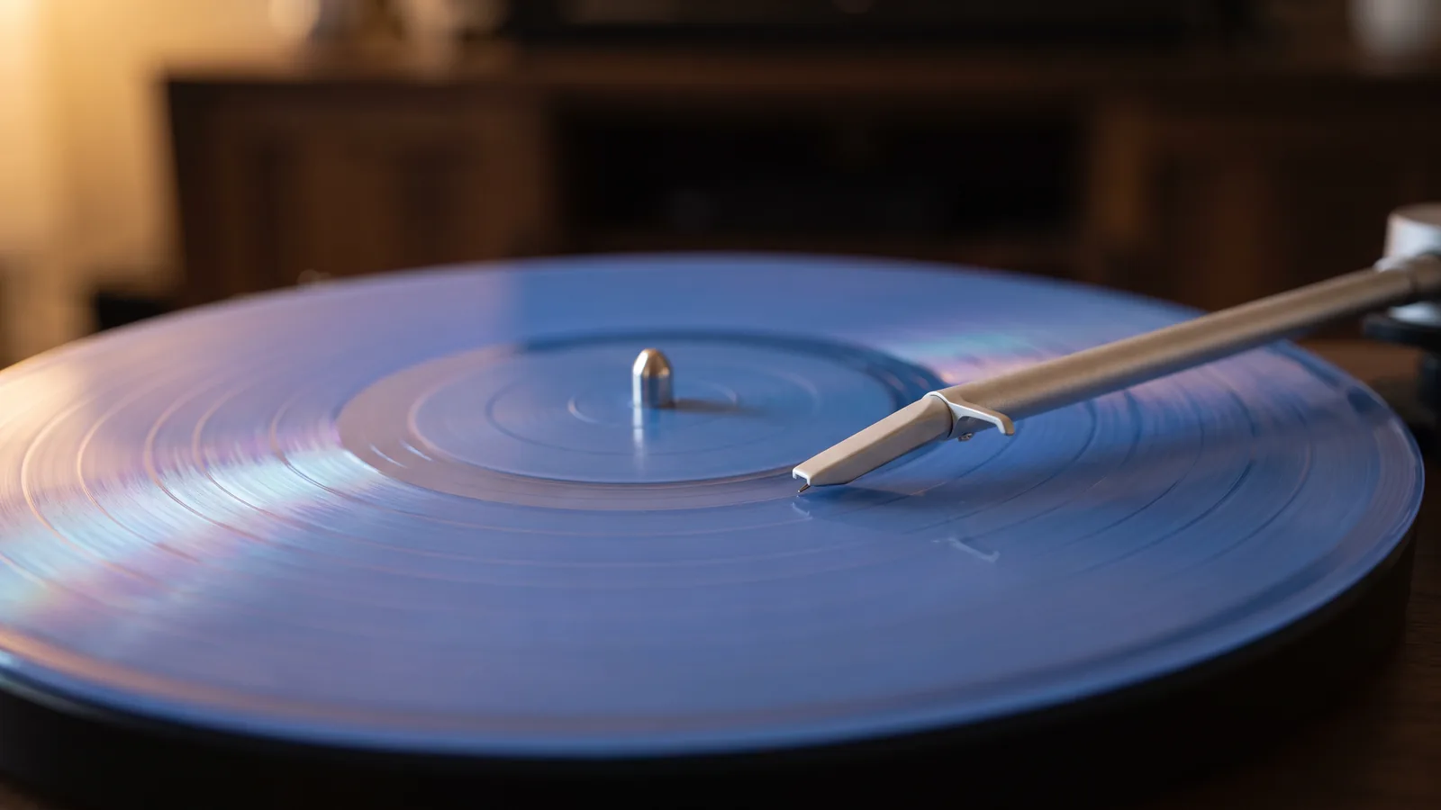 A record player's stylus rests in the groove of a spinning blue vinyl record.